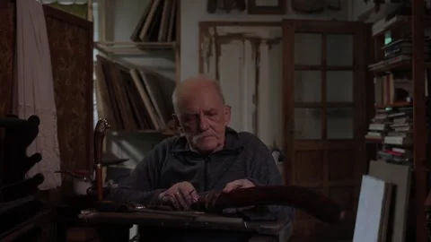 Elderly craftsman working in his old workshop, restoring bladed weapons Stock Footage 328408184