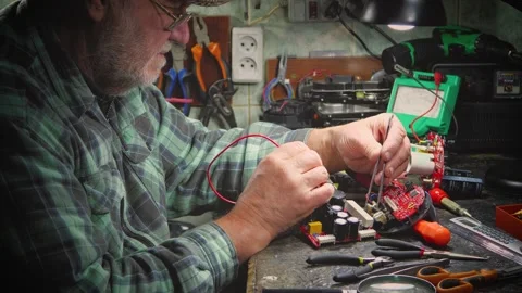 An elderly craftsman, in a workshop, repairs an old clock mechanism Stock Footage 294834075