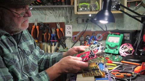 An elderly craftsman, in a workshop, repairs an old clock mechanism Stock Footage 294834149
