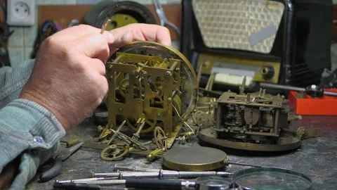 An elderly craftsman, in a workshop, repairs an old clock mechanism Stock Footage 294834696