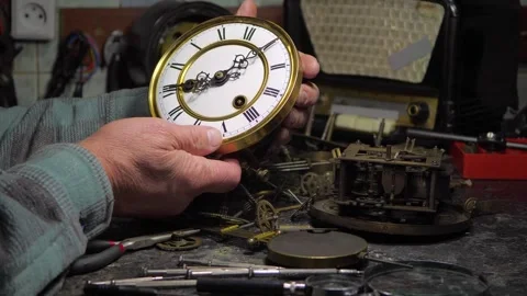 An elderly craftsman, in a workshop, repairs an old clock mechanism Stock Footage 294834752