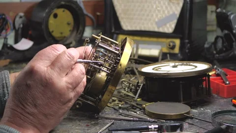 An elderly craftsman, in a workshop, repairs an old clock mechanism Stock Footage 294834897