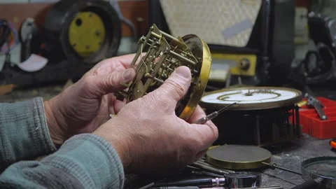 An elderly craftsman, in a workshop, repairs an old clock mechanism Stock Footage 294834998