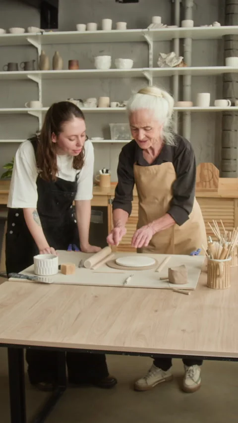 Elderly Craftswoman and Apprentice Cutting Clay Shapes in Studio Stock Footage 331811047