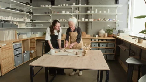 Elderly Craftswoman and her Apprentice Shaping Clay in Modern Pottery studio Stock Footage 331805487