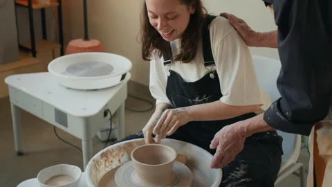 Elderly Craftswoman Supporting Beginner Potter in workshop Stock Footage 331798732