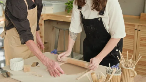 Elderly Craftswoman Teaching Apprentice to Roll Out Clay in Pottery Workshop Stock-Footage 331802473