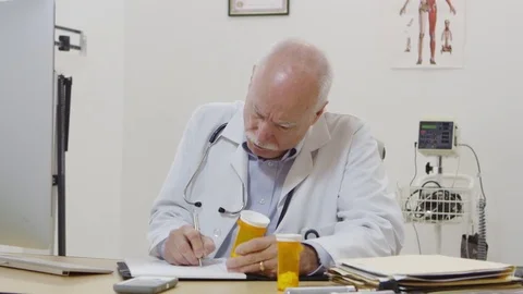 Elderly doctor checking perscriptions and writing notes Video stock 80128886