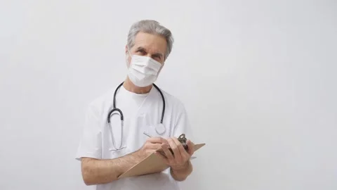 Elderly doctor man makes notes wearing stethoscope isolated on white. Stock Footage 146986065
