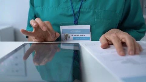 Elderly doctor typing on tablet PC, filling data in online medical records Stockbeeldmateriaal 118903405