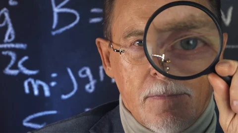 Elderly elegant professor looking through a magnifying glass at camera Stock Footage 130049727