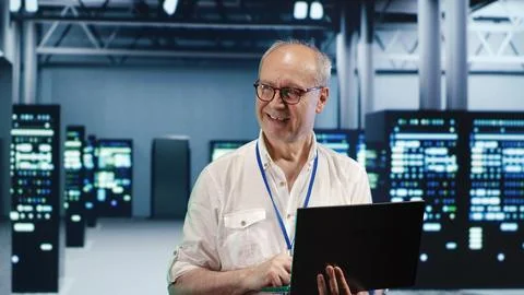 Elderly engineer optimizes data center Stock Photos