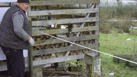 An elderly farmer measuring the length with a long tape measure. Stock Footage 157286984