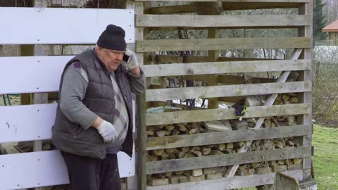 An elderly farmer is talking on a smartphone in the backyard. Stock Footage 157286936