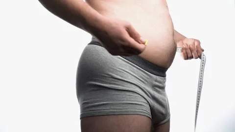 Overweight man measuring waist with measure tape, close up image. Weight  loss, motivation, fat burning Stock Photo