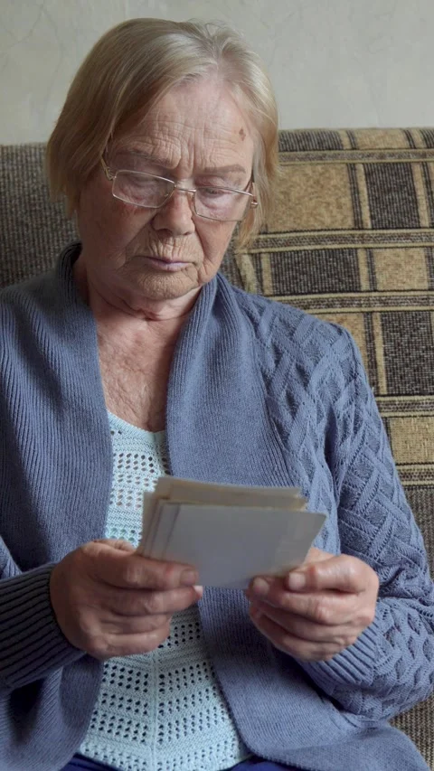 Elderly female browsing old black white photos reminiscing about past Video stock 314466853