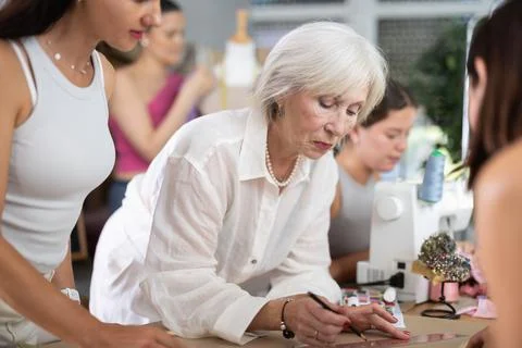 Elderly female teacher explains to group how to draw pattern Stock Photos