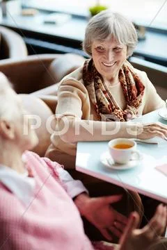 Elderly females talking by tea in cafe Stock Photos
