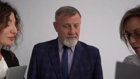 Elderly gray-bearded man talks to two subordinate women. Successful Stock Footage 152647865