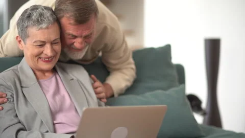 Elderly gray-haired man and woman have a video call while sitting on the couch Stock Footage 169520024