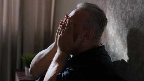 Elderly gray-haired man depressed sitting on bed at home Stock Footage 265707819
