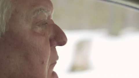 An elderly gray-haired man drives off-road in winter. Close-up of a man's face. Stock Footage 150315604