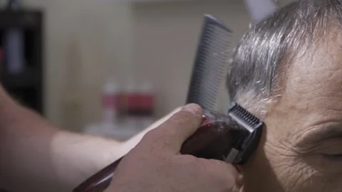 An elderly gray-haired man gets a haircut in the salon. 스톡 동영상 164734420