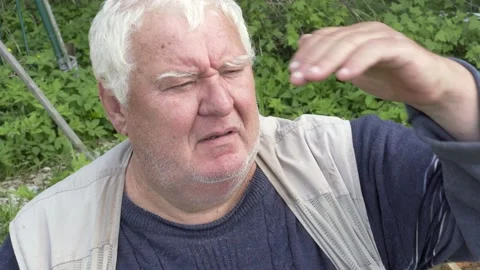 Elderly gray-haired man holding hand above eyes, peering into distance. Stock Footage 157287437