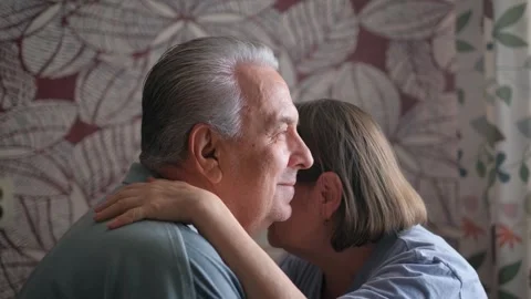An elderly gray-haired man hugging his wife in a room Stock Footage 317772278