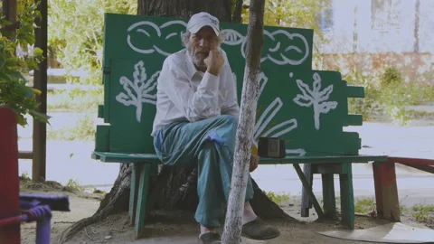 An elderly gray-haired man lonely sits on the street Video stock 87147619