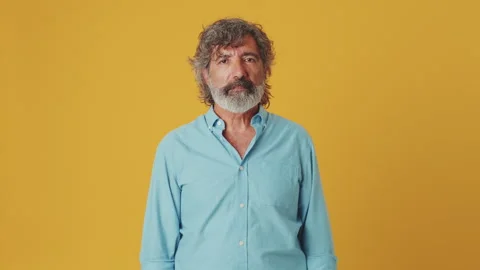 Elderly grey-haired bearded man looking at camera, isolated on orange background Stock Footage 252503468