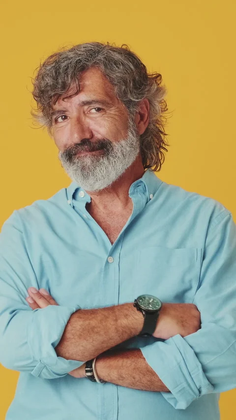 Elderly grey-haired man looking at camera smiling showing heart sign isolated on Stock Footage 250841276