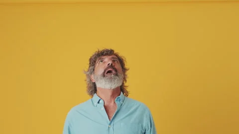 Elderly grey-haired man looking up at the copy space workspace area, isolated on Stock Footage 252207563