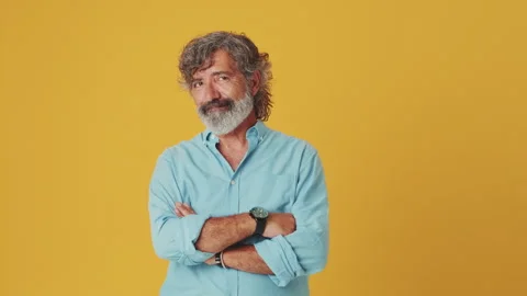 Elderly grey-haired man looking at camera smiling showing heart sign isolated on Stock Footage 252207576