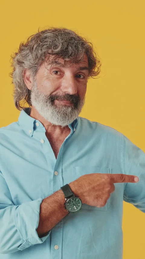 Elderly grey-haired man pointing fingers towards advertising space, isolated on Stock Footage 252031061