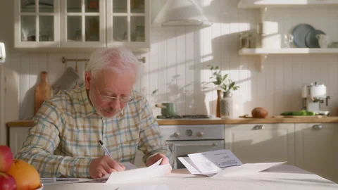 Elderly grey haired man sits at table with papers Video stock 264834126