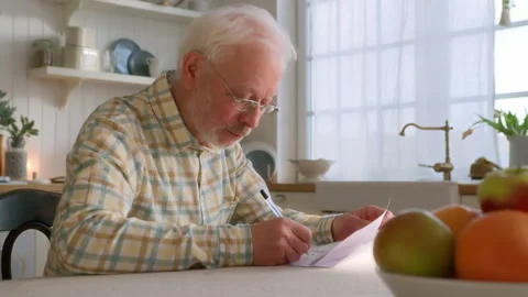 Elderly grey haired man sits at table with papers Stock Footage 264835793