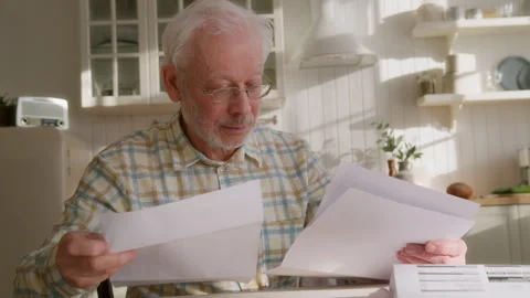 Elderly grey haired man sits at table with papers Stock Footage 264837706