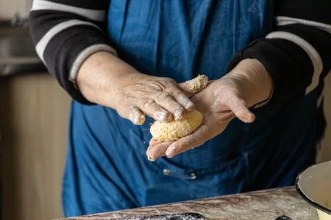 Elderly hands carefully shape fresh cottage cheese pancakes on a floured su.. Stock Photos