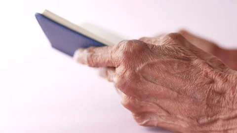 Elderly hands holding passport document against pink background in soft light Stock Footage 333151920