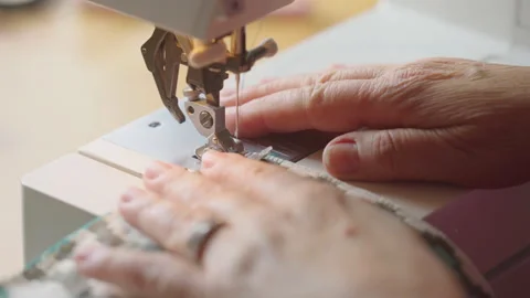 Elderly Hands Operating a Sewing Machine on Patterned Fabric Stock Footage 336709950