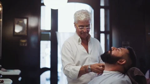 Elderly handsome barber working in old style shop and drying hair of customer Stock Footage 71824081