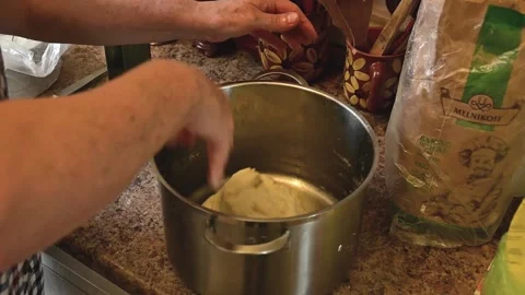 Elderly hostess's hands beating out yeast dough, hitting it on bottom of pan Stock Footage 140678028