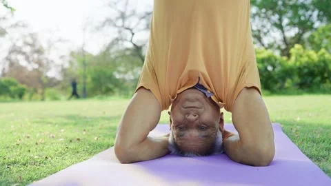 Elderly Indian man Performing Headstand in Garden in morning sunlight Stock Footage 247999875