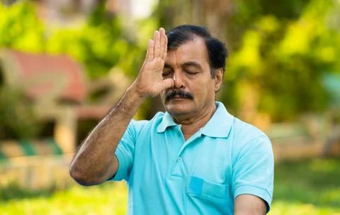 Elderly Indian senior man doing nostril breathing yoga or pranayama exercise - Stock Photos