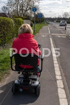 An elderly lady in a red coat enjoying the freedom of an electric mobility Stock Photos