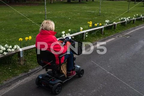 An elderly lady in a red coat enjoying the freedom of an electric mobility Stock Photos