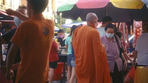 Elderly lady talking to a buddhist monk at Eng Ann morning market Stock Footage 231761752