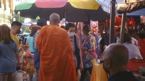 Elderly lady talking to a buddhist monk at Eng Ann morning market Stock Footage 231761856