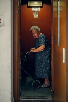 Elderly lady with walker enters elevator Stock Photos